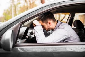 person sitting in a car with head on steering wheel stressed in traffic jam